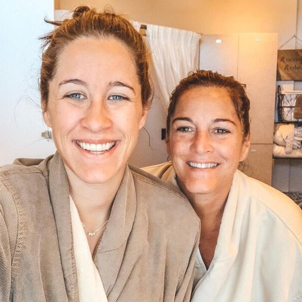 Two women in bathrobes taking a selfie in a bathroom.